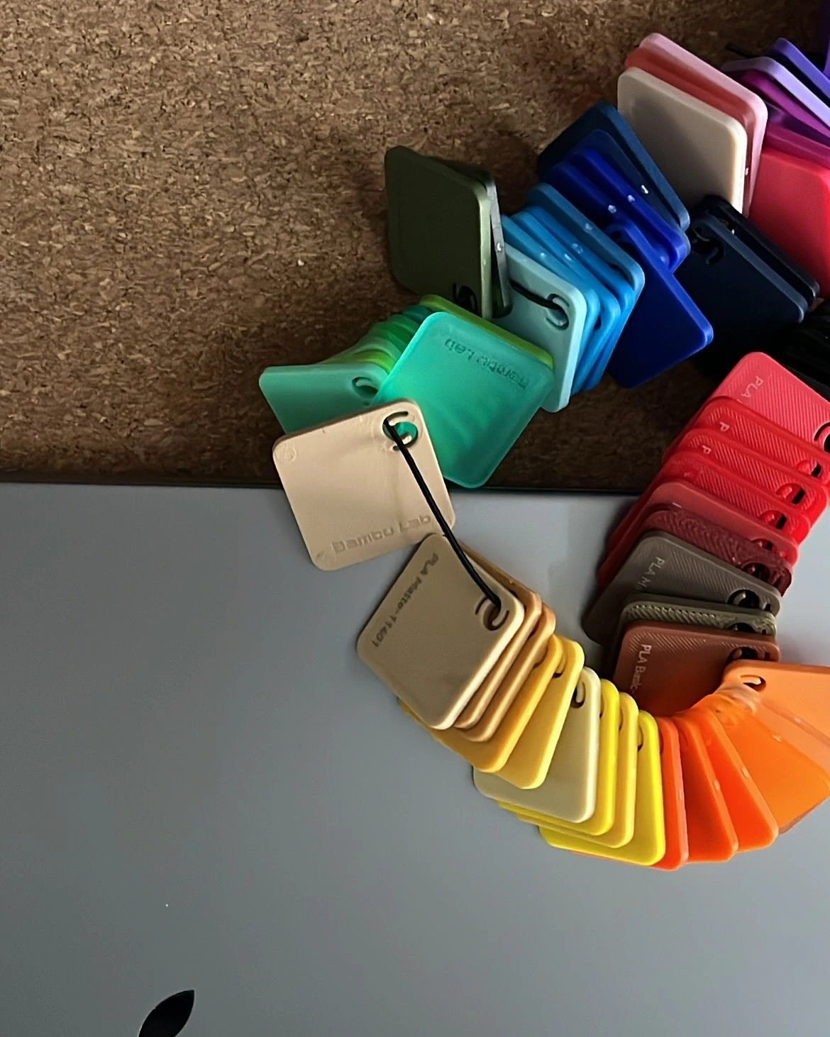 Fan of filament colour swatches on a cork board